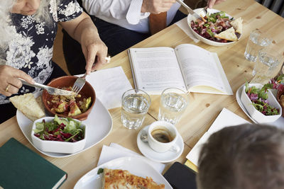 High angle view of friends having food at table in book club