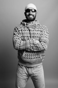 Portrait of young man standing against gray background