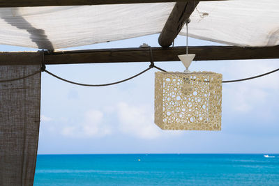 Close-up of wooden post hanging on sea against sky