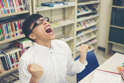 Angry male student shouting while sitting at table in library