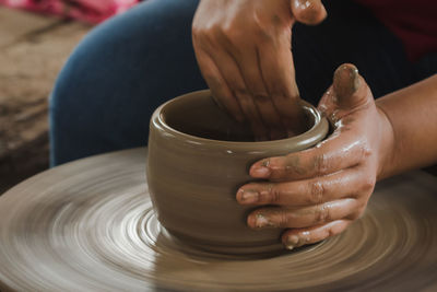 Cropped hand of man molding shape on pottery wheel