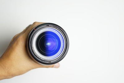 Close-up of hand holding camera against white background