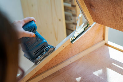 Hand sanding wood with a machine in the craftsman workshop.