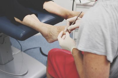 Midsection of woman doing pedicure of customer in beauty spa