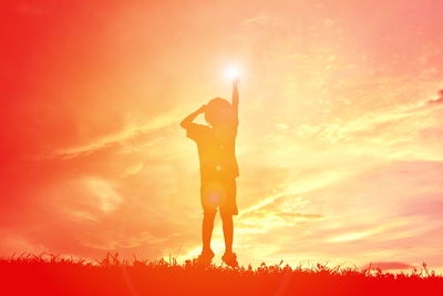 Silhouette girl jumping on field against sky during sunset