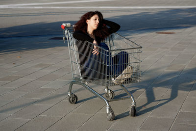 View of woman sitting in shopping cart outdoors