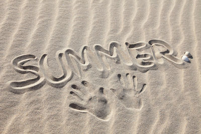 Text and handprints on sand at beach