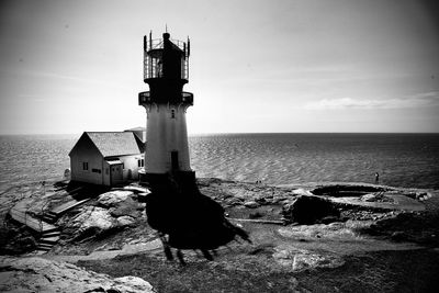 Lighthouse by sea against sky