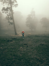 Man standing on field against trees