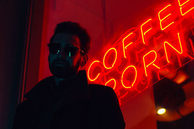 Portrait of man wearing sunglasses while standing against restaurant