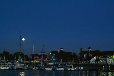 Boats moored at harbor against clear sky at night