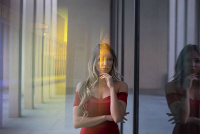 Portrait of a young woman standing against curtain