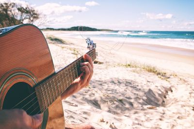 Man holding guitar on beach