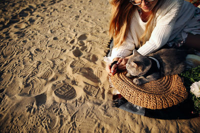 Midsection of woman with dog on sand