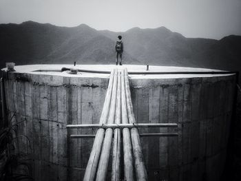 Rear view of man standing on storage tank
