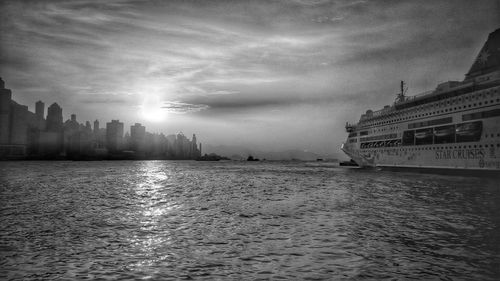 View of buildings by sea against cloudy sky