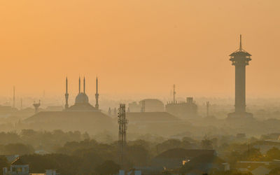 Communications tower in city during sunset