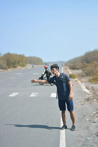 Full length of man skateboarding on road against clear sky