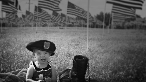 Portrait of little girl siting against american flags on field