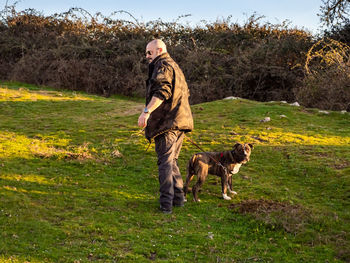 Man with dog on grass against trees