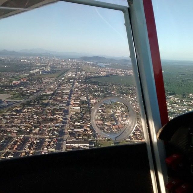 window, indoors, glass - material, transparent, cityscape, architecture, aerial view, sky, transportation, city, built structure, airplane, travel, vehicle interior, looking through window, mode of transport, air vehicle, no people, day, part of