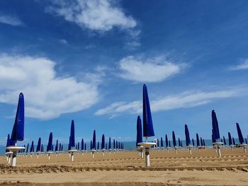 Wooden posts on beach against blue sky