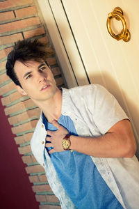 Thoughtful young man standing against door