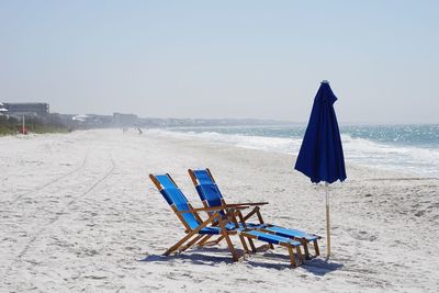 Deck chairs on beach against clear sky