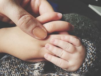 Cropped image of mother holding baby hand