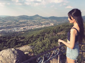 Side view of young woman looking towards mountains from observation point
