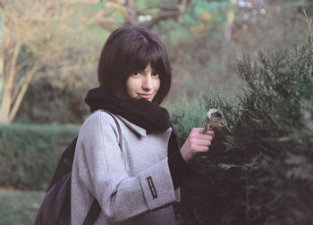 Portrait of smiling young woman wearing warm clothes while standing on field