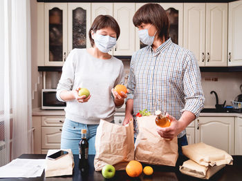 Young couple in masks is at kitchen. food delivery in conditions of quarantine coronavirus covid19.