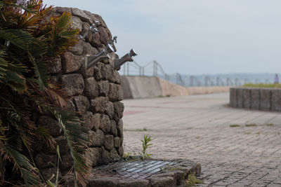Close-up of stone wall by rocks against sky
