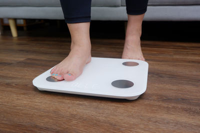 Low section of woman standing on table at home