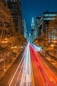 Light trails on road amidst buildings in city at night