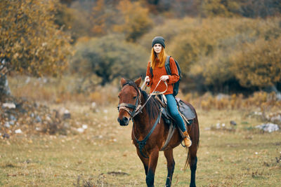 Close-up of young woman riding horse on field