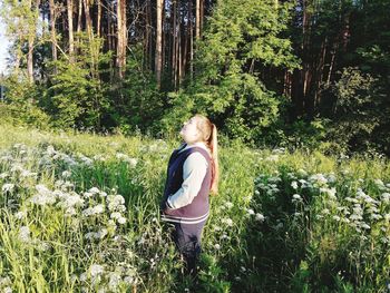 Rear view of woman standing amidst trees in forest