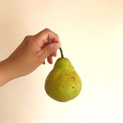 Close-up of hand holding apple against white background