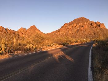 Road by mountains against clear sky