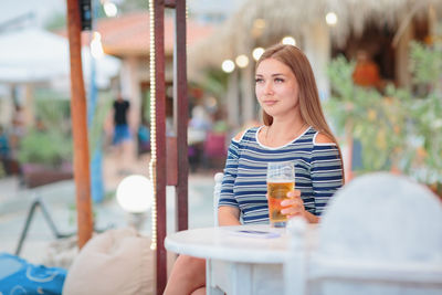 Portrait of woman drinking beer at beach cafe