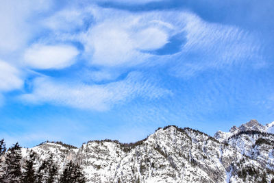 Low angle view of snowcapped mountains against blue sky