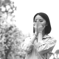 Woman covering mouth against clear sky