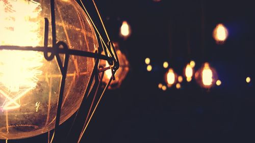 Close-up of illuminated light bulb against sky at night