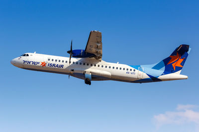 Low angle view of airplane flying against clear blue sky