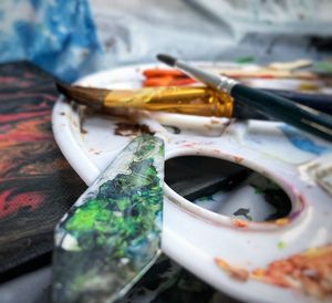 Close-up of messy paintbrushes and palette on table