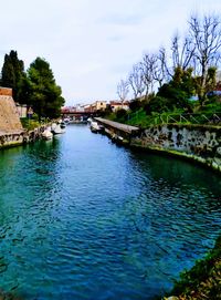 Scenic view of river by buildings against sky