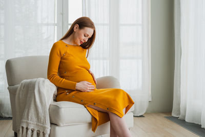 Young woman sitting on sofa at home