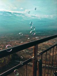 Close-up of raindrops on railing against sea