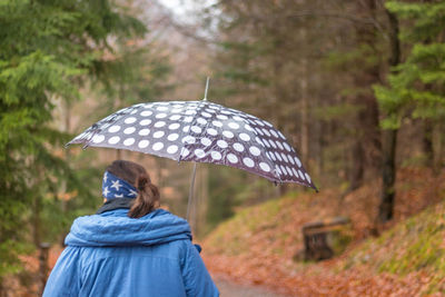 Rear view of woman with umbrella standing on rainy day