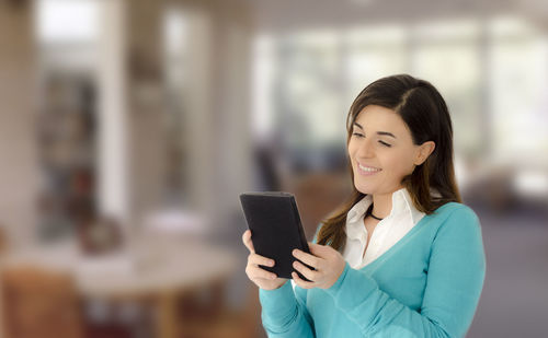 Business woman using digital tablet while standing in office